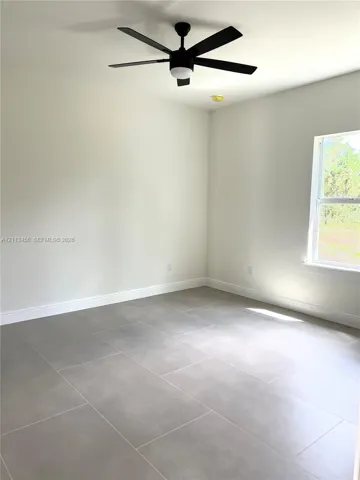 Neutral-toned interior featuring large-format tile flooring, matte black ceiling fan with integrated lighting, and energy-efficient window