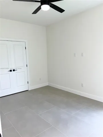 Neutral-toned tile flooring, double-panel doors with matte black hardware, and a ceiling-mounted light fixture with a fan