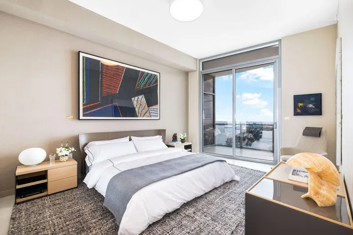 Full-height sliding glass doors with access to a private balcony, neutral wall finishes, and overhead recessed lighting