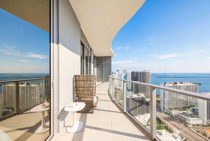 Curved balcony featuring large-format tile flooring and a glass-paneled railing system with a metal frame