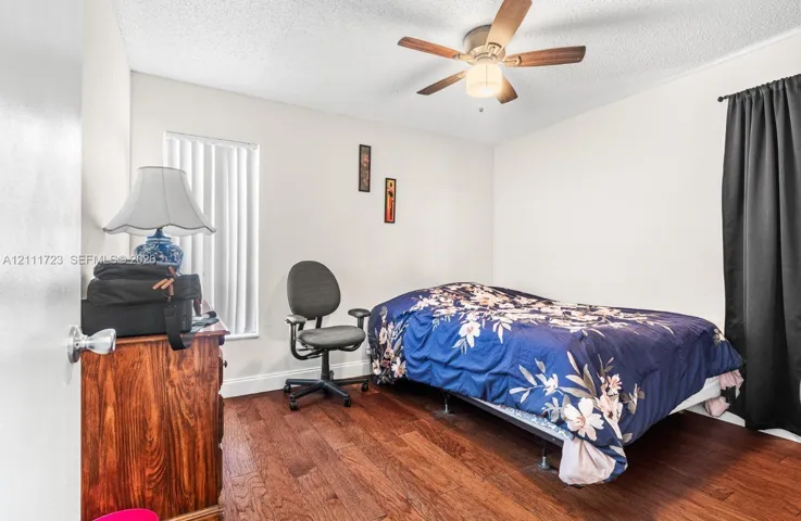 Interior room featuring wood-finish flooring, a ceiling fan with integrated lighting, and vertical window blinds