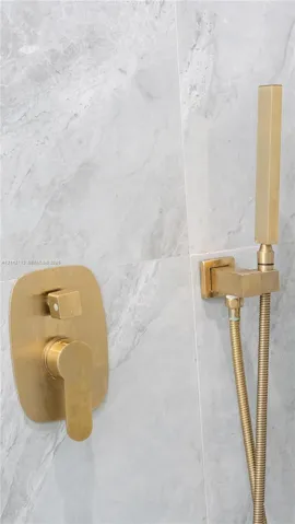 Wall-mounted shower fixture featuring a brushed metallic finish, single-handle mixing valve, and adjustable handheld spray wand, set against large-format, light-toned stone-patterned wall tile