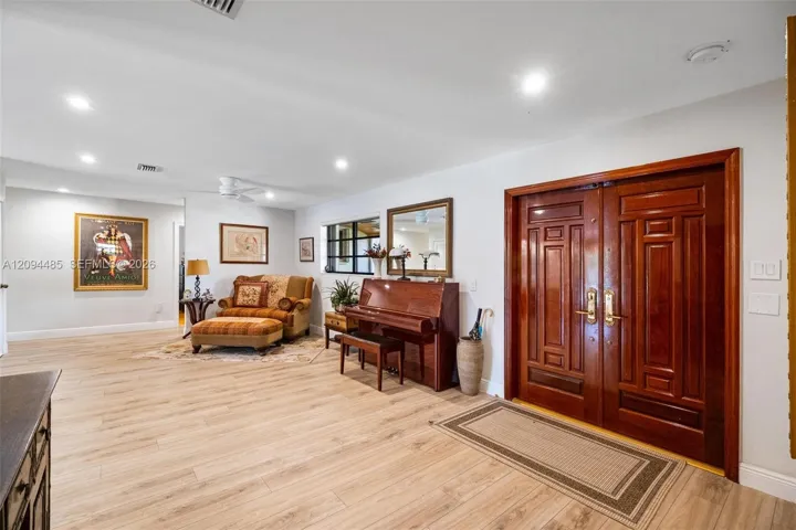 Double-entry front doors with polished wood finish, wood-finish flooring, and recessed ceiling lighting