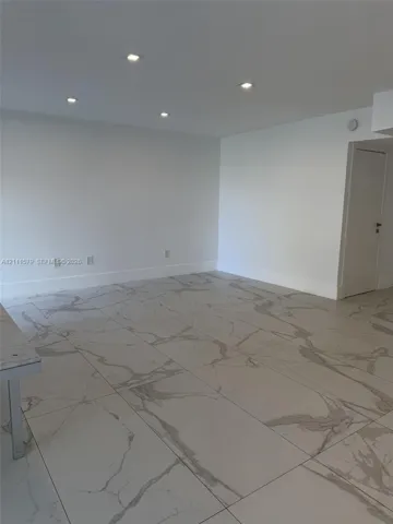Neutral-toned large-format tile flooring with marble-pattern veining, complemented by recessed ceiling lighting