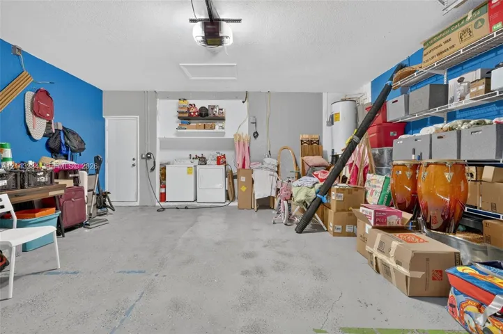 Garage interior featuring concrete flooring, an overhead door opener, a dedicated laundry area, and integrated metal shelving