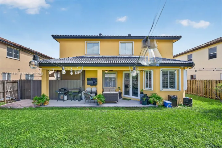 Rear exterior featuring a covered patio, tile roof, and enclosed backyard with wood-style fencing