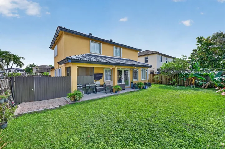 Two-story exterior with a tiled roof, a covered concrete patio, and a fenced backyard