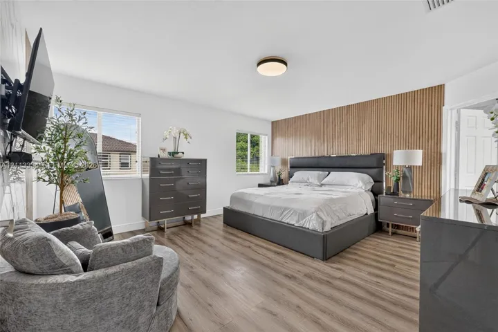 Wood-finish flooring, vertical wood-slat accent wall, and flush-mount ceiling lighting
