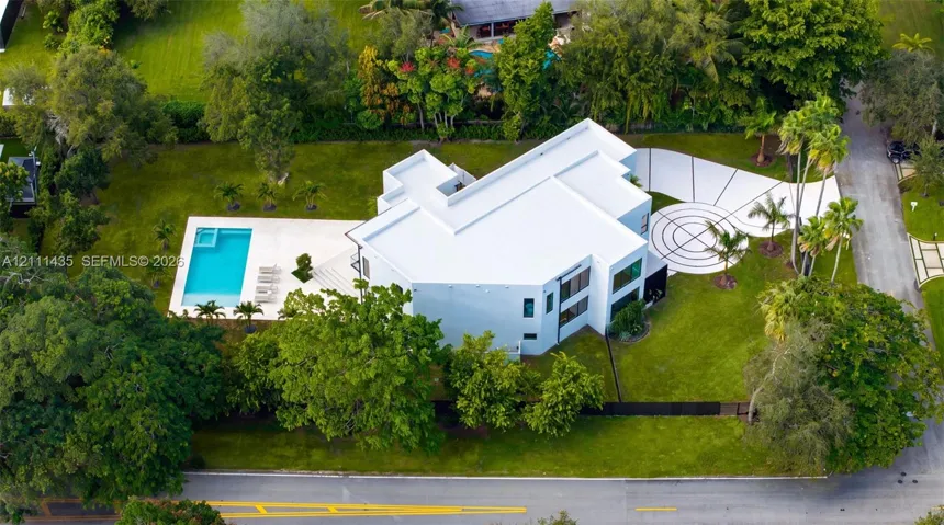 Modern multi-level estate featuring a flat-roof architectural design, a private swimming pool with an integrated spa, expansive lawn, and a decorative concrete driveway with geometric detailing