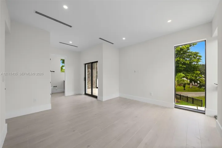 Neutral-toned wood-finish flooring, recessed lighting, floor-to-ceiling window, and sliding glass door