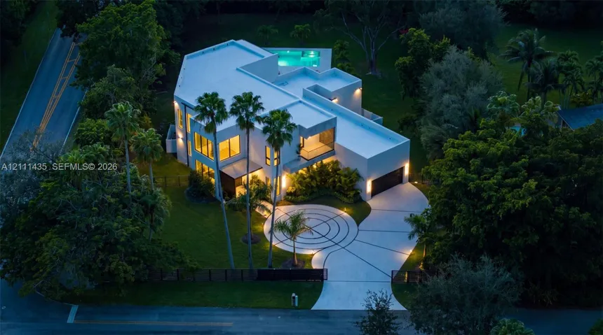 Contemporary multi-level residence featuring a flat roofline, circular decorative concrete driveway, attached multi-car garage, and an elevated swimming pool