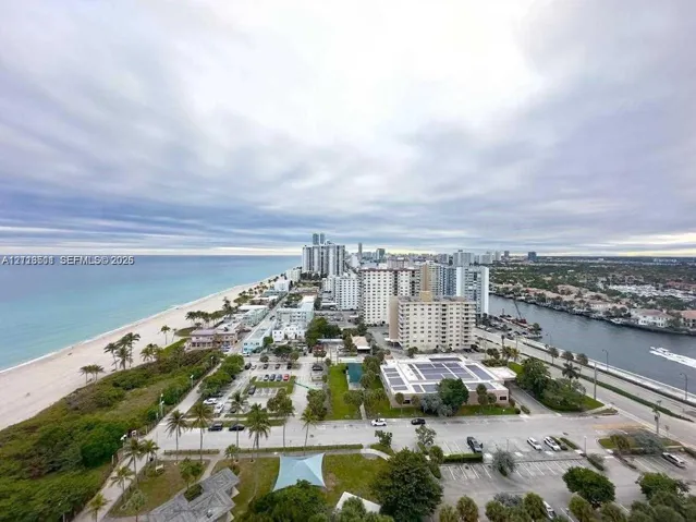 Aerial coastal perspective featuring ocean shoreline, sandy beach, integrated waterway, and metropolitan skyline