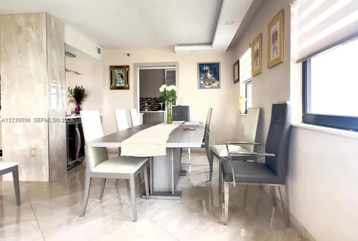 Dining area featuring polished stone-finish flooring, a full-height stone-clad column, recessed ceiling lighting, and built-in under-counter beverage refrigeration