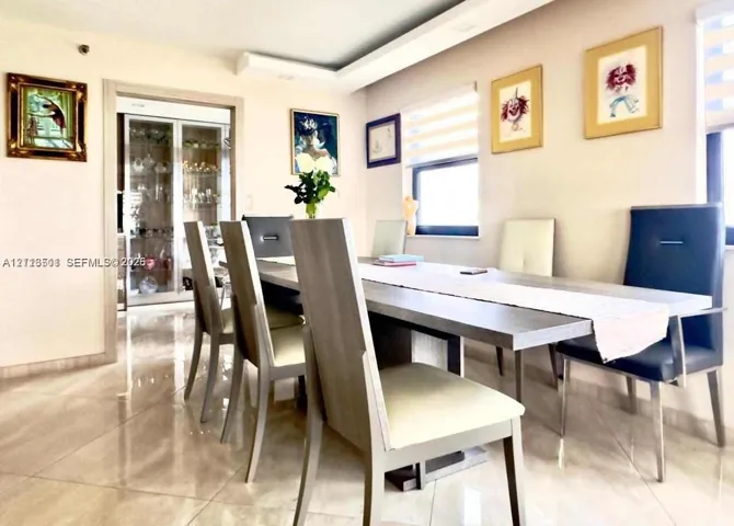 Polished large-format tile flooring, recessed tray ceiling, and built-in glass-paneled cabinetry