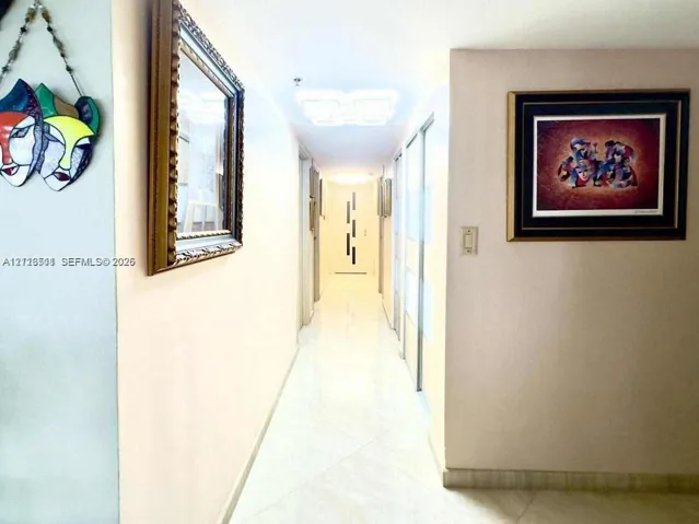 Hallway featuring tile flooring, ceiling-mounted light fixtures, and floor-to-ceiling mirrored closet doors