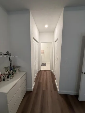 Hallway featuring wood-finish flooring, two sets of white bi-fold closet doors, and recessed lighting