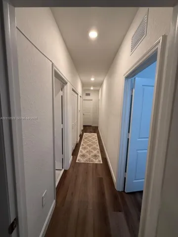 Hallway featuring wood-finish flooring, recessed lighting, and white multi-panel interior doors
