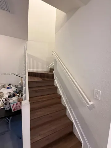 Staircase featuring wood-finish treads and white painted handrails