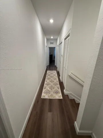 Hallway featuring wood-finish flooring, recessed ceiling lighting, and white louvered closet doors
