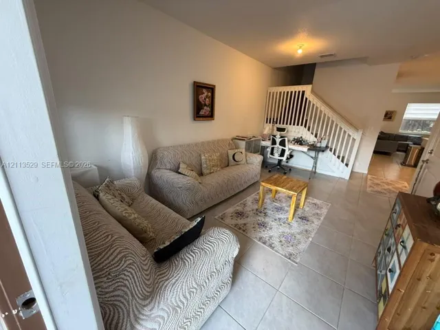 Interior space featuring large-format ceramic tile flooring and a staircase with white wooden balustrades
