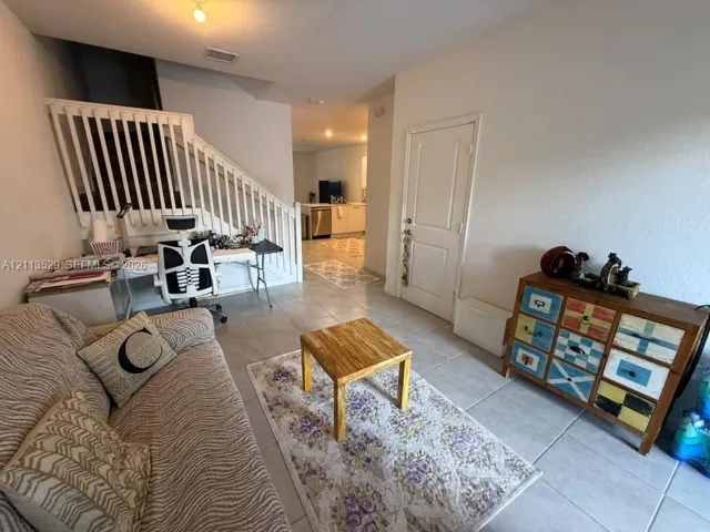 Ceramic tile flooring throughout with a white wooden staircase railing and a panel-style interior door