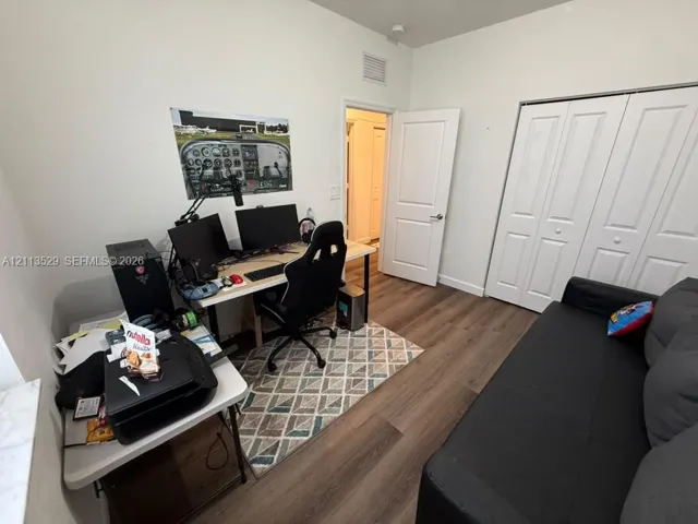 Room featuring wood-finish flooring, a two-panel interior door, and a bi-fold closet with white panel doors
