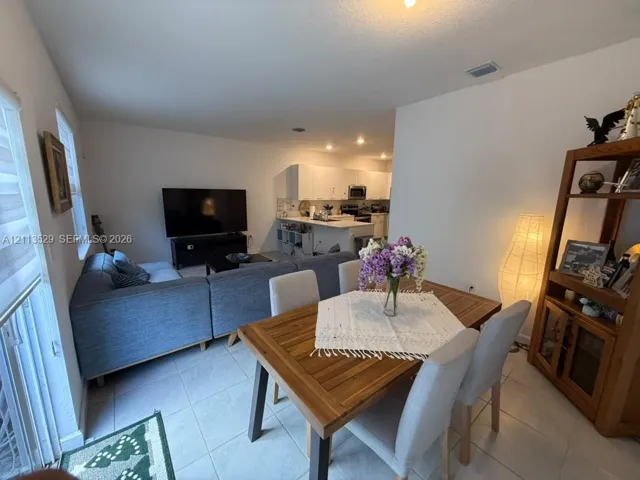Open-concept layout featuring light-toned tile flooring, recessed lighting, and white cabinetry