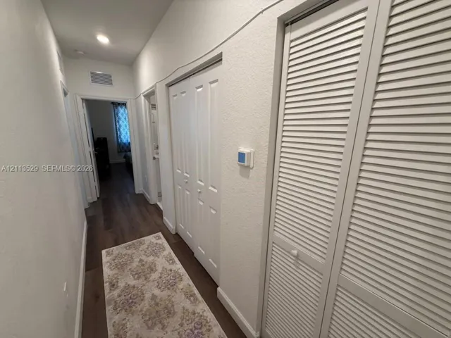 Hallway featuring wood-finish flooring, dual sets of bi-fold closet doors, and recessed lighting