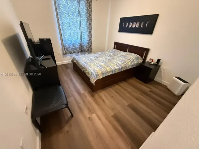 Interior space featuring wood-finish flooring and a single window with a geometric-patterned treatment