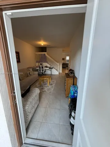Interior featuring neutral tile flooring and a staircase with white balusters