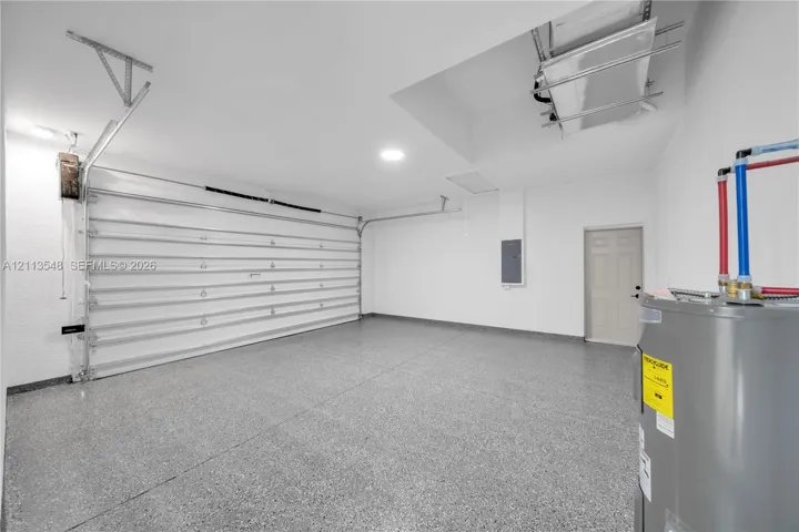 Garage featuring epoxy-coated flooring, insulated sectional garage door, recessed lighting, and water heater
