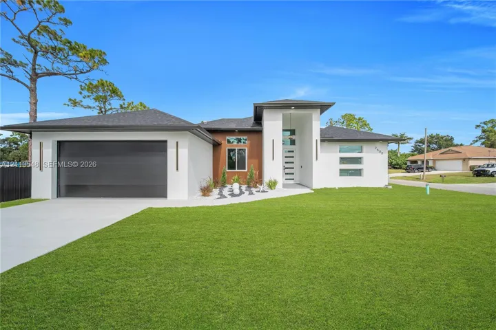 Contemporary exterior featuring smooth stucco finish, vertical wood-paneling accents, horizontal glass-paneled entry door, clean-lined rooflines, and a paved concrete driveway