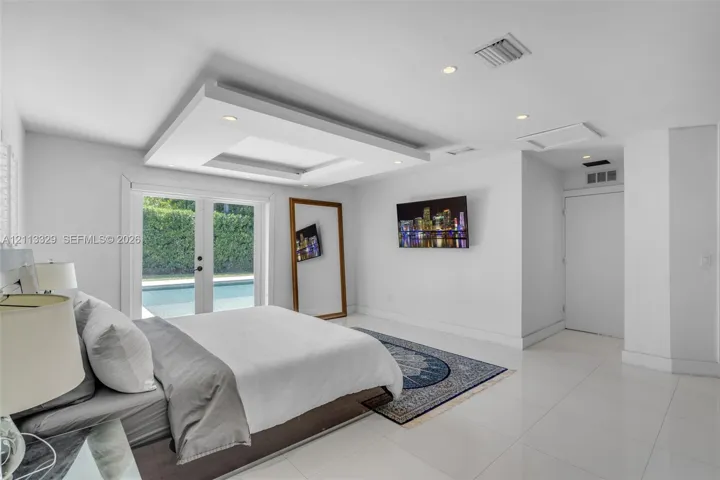 Tray ceiling with recessed lighting, tile flooring, and glass-paneled double doors providing outdoor access
