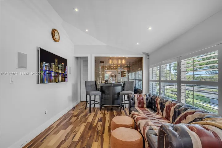 Vaulted ceilings with recessed lighting, wood-finish flooring, glass-enclosed storage area, and plantation shutters