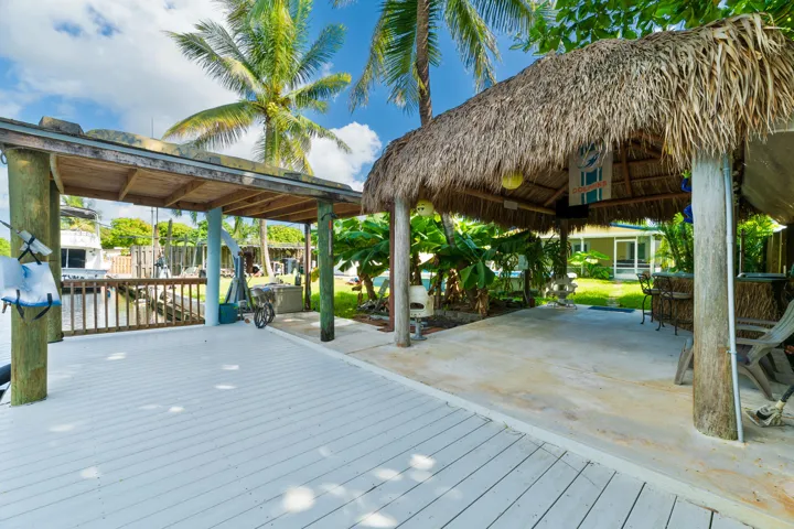 Waterfront dock featuring composite decking, a thatched-tiki
