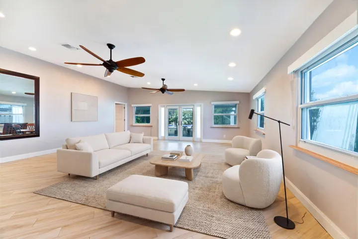 Virtually Staged great room featuring ceramic plank flooring, recessed lighting, double ceiling fans, and glass-paned double doors