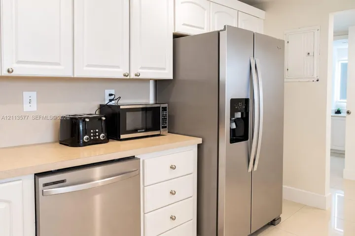 Kitchen featuring white cabinetry, neutral-toned countertops, and stainless steel appliances including a side-by-side refrigerator and dishwasher