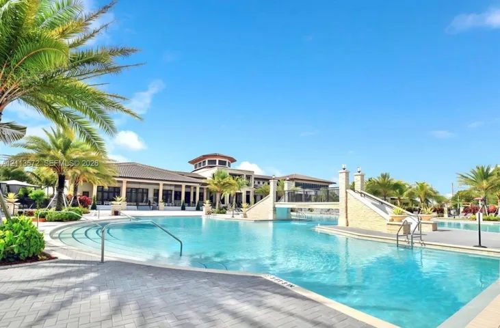 Swimming pool with stone-clad bridge, tiered entry steps, metal handrails, and paver decking
