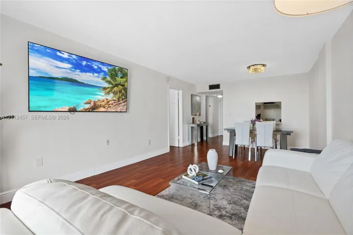Living area featuring wood-finish flooring, recessed lighting, and a service pass-through opening to the kitchen