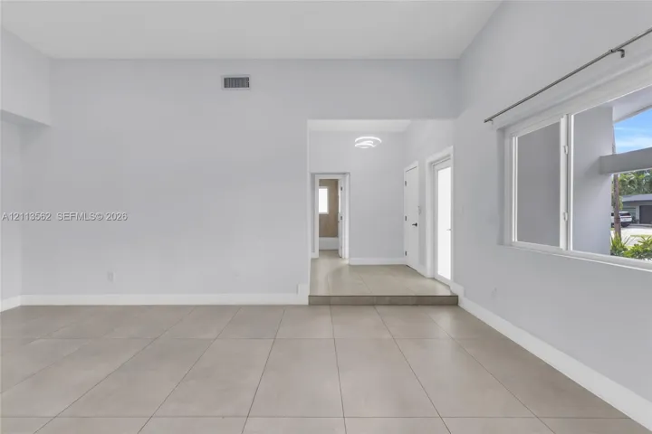 Open-concept interior featuring large-format ceramic tile flooring, vaulted ceilings, and horizontal sliding windows