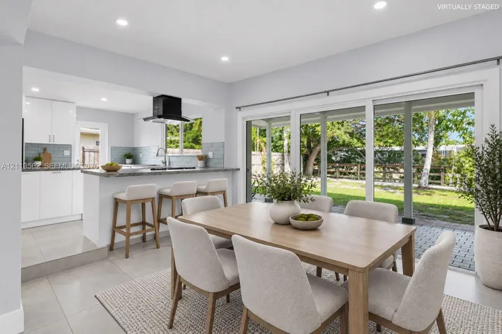 Kitchen featuring a peninsula with countertop seating, tiled backsplash, recessed lighting, and sliding glass doors leading to a paved patio