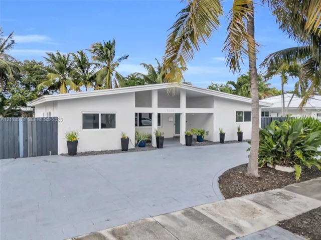 Mid-century modern exterior featuring a low-pitch roofline, expansive covered entryway, and stone-paved circular driveway