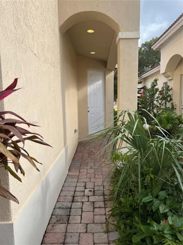 Covered entryway featuring a stucco facade, arched architectural detail, recessed lighting, and a paver stone walkway