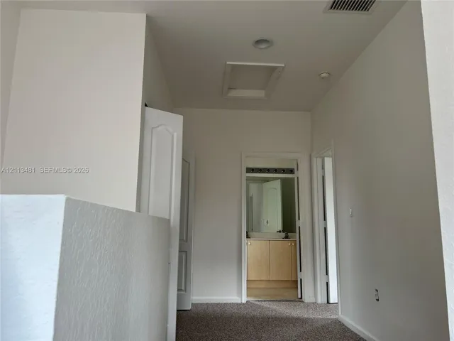 Hallway featuring neutral-toned carpeting, recessed ceiling lighting, and six-panel interior doors