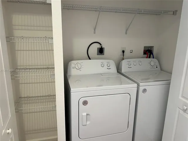 Laundry space featuring white top-load appliances and built-in wire shelving units