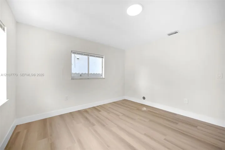 Neutral interior room featuring wood-finish flooring, a recessed ceiling light, and horizontal sliding windows