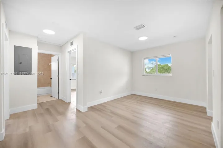 Interior space featuring wood-finish flooring, recessed ceiling lighting, and a window with exterior greenery