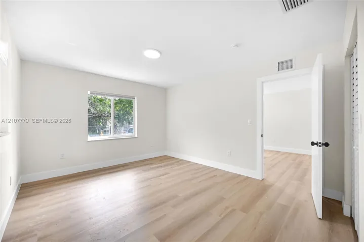 Neutral interior featuring wood-finish flooring, crisp off-white walls, and a window with natural light exposure