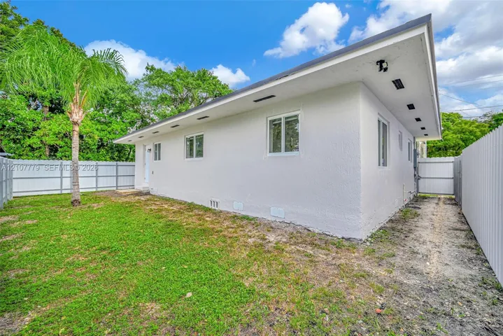 White stucco exterior with a shed roofline, vinyl fencing, and open lawn area