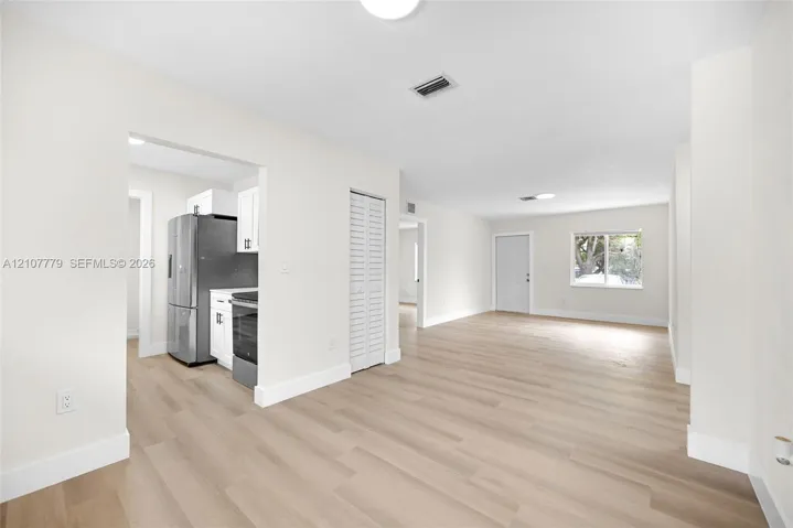 Open floor plan featuring wood-finish flooring, stainless steel kitchen appliances, white cabinetry, and recessed lighting